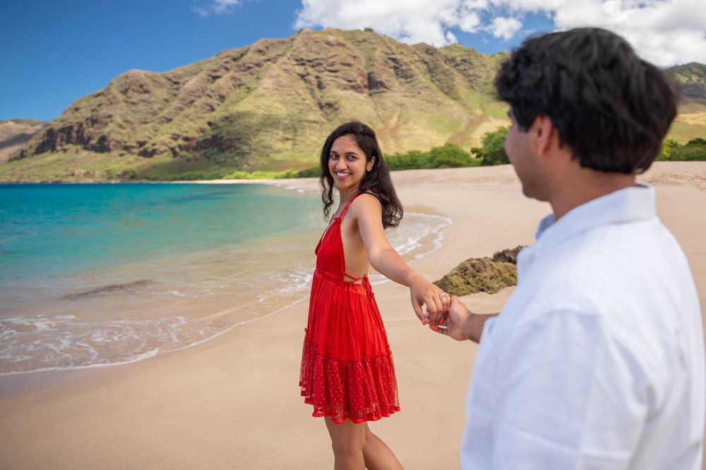 Two people share a romantic moment on a pristine beach with turquoise water and mountains at Makua Beach.