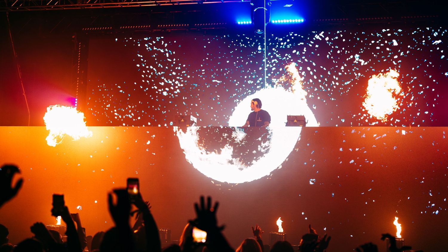 Vibrant concert stage lighting creates a dramatic silhouette effect against a colorful backdrop during a live performance.
