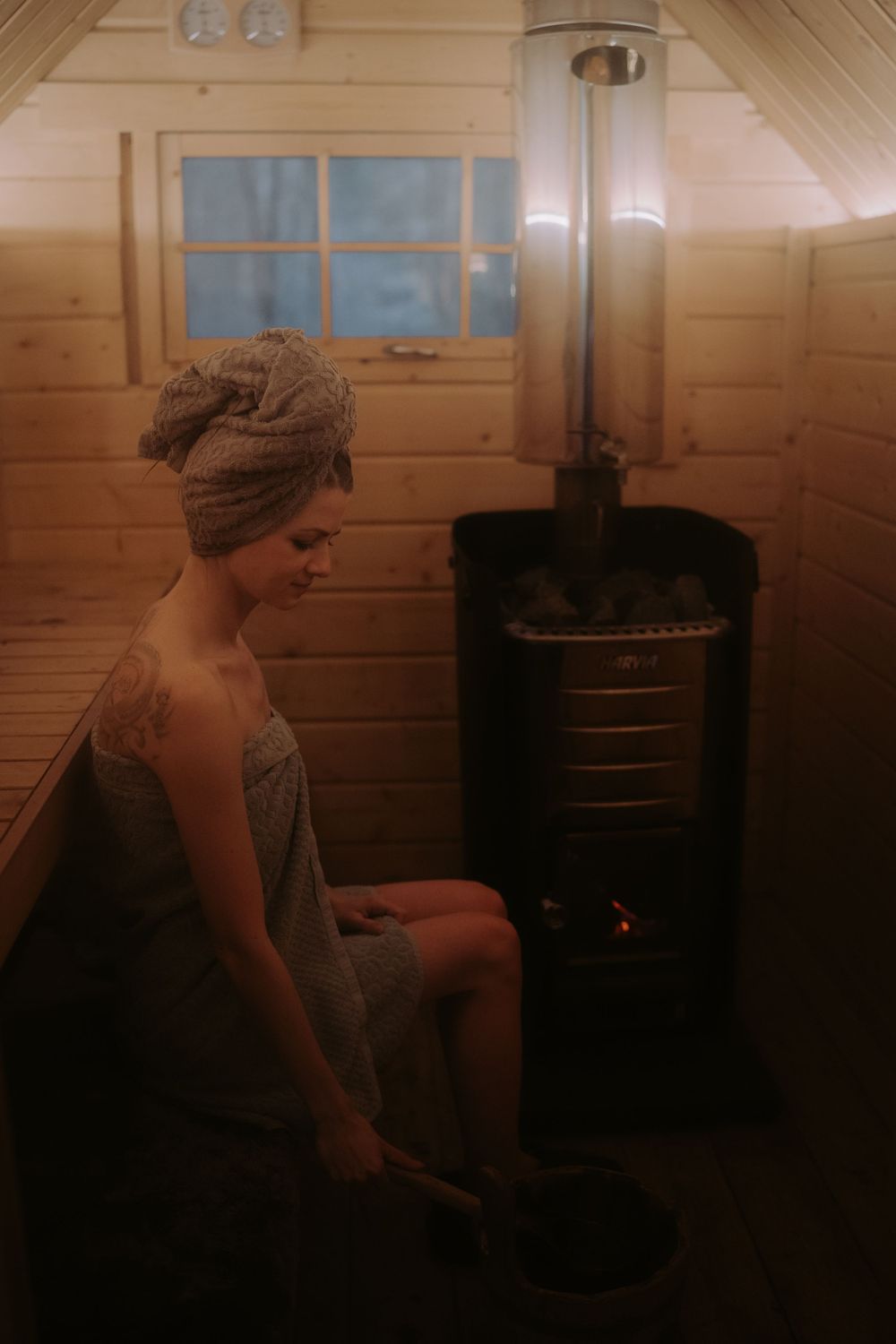 Person relaxing by a wood stove in a rustic cabin interior.