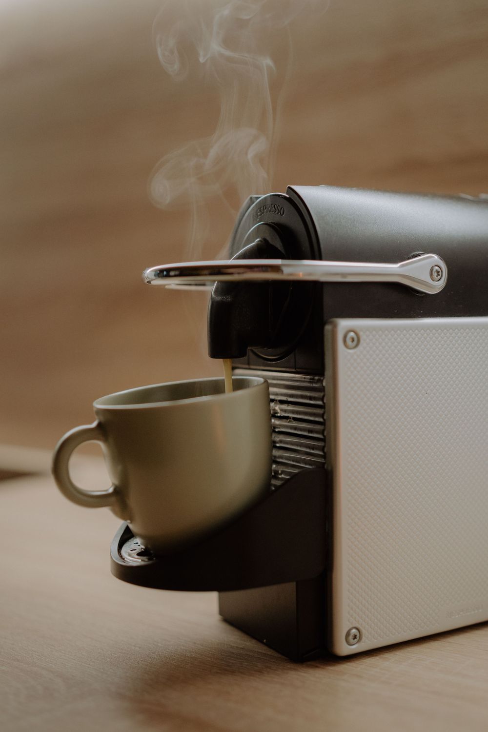 Steaming espresso machine brewing coffee into a gray ceramic cup.
