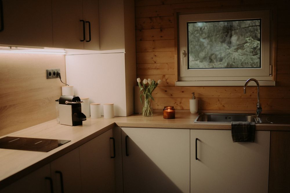 Modern kitchen interior with wooden accents, white cabinets, and soft lighting creating a cozy atmosphere.
