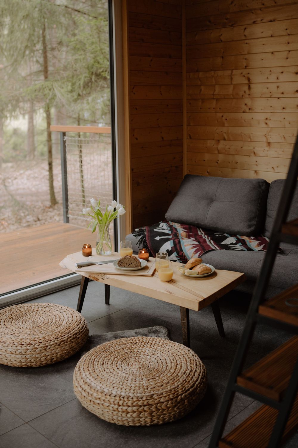 Cozy seating area with woven floor cushions and wooden coffee table by large window.