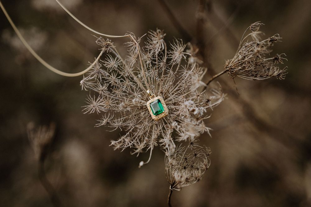 Emerald pendant necklace artistically displayed on dried Queen Anne's lace flower.