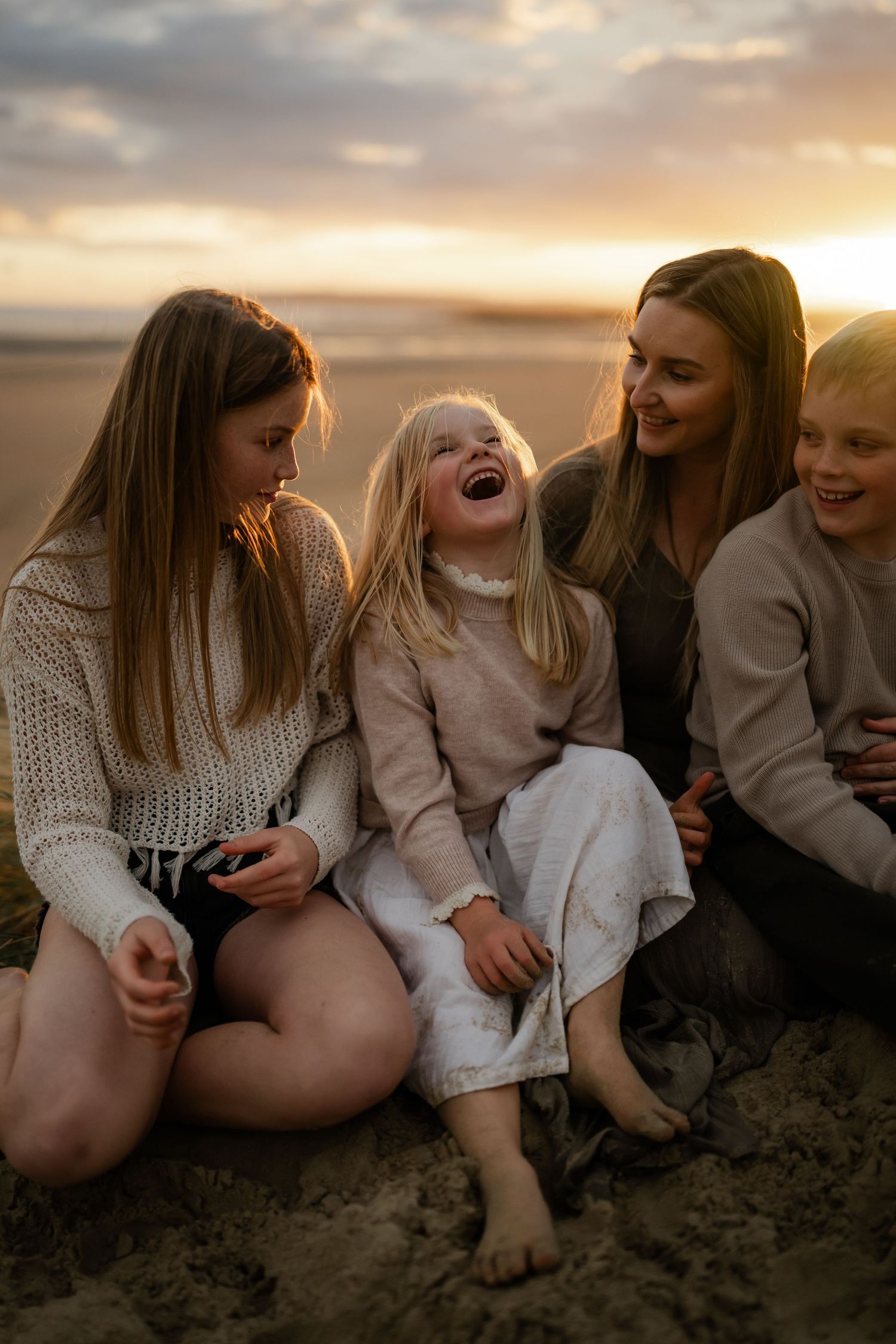A family laughing in the sand on the beach, kent family photographer