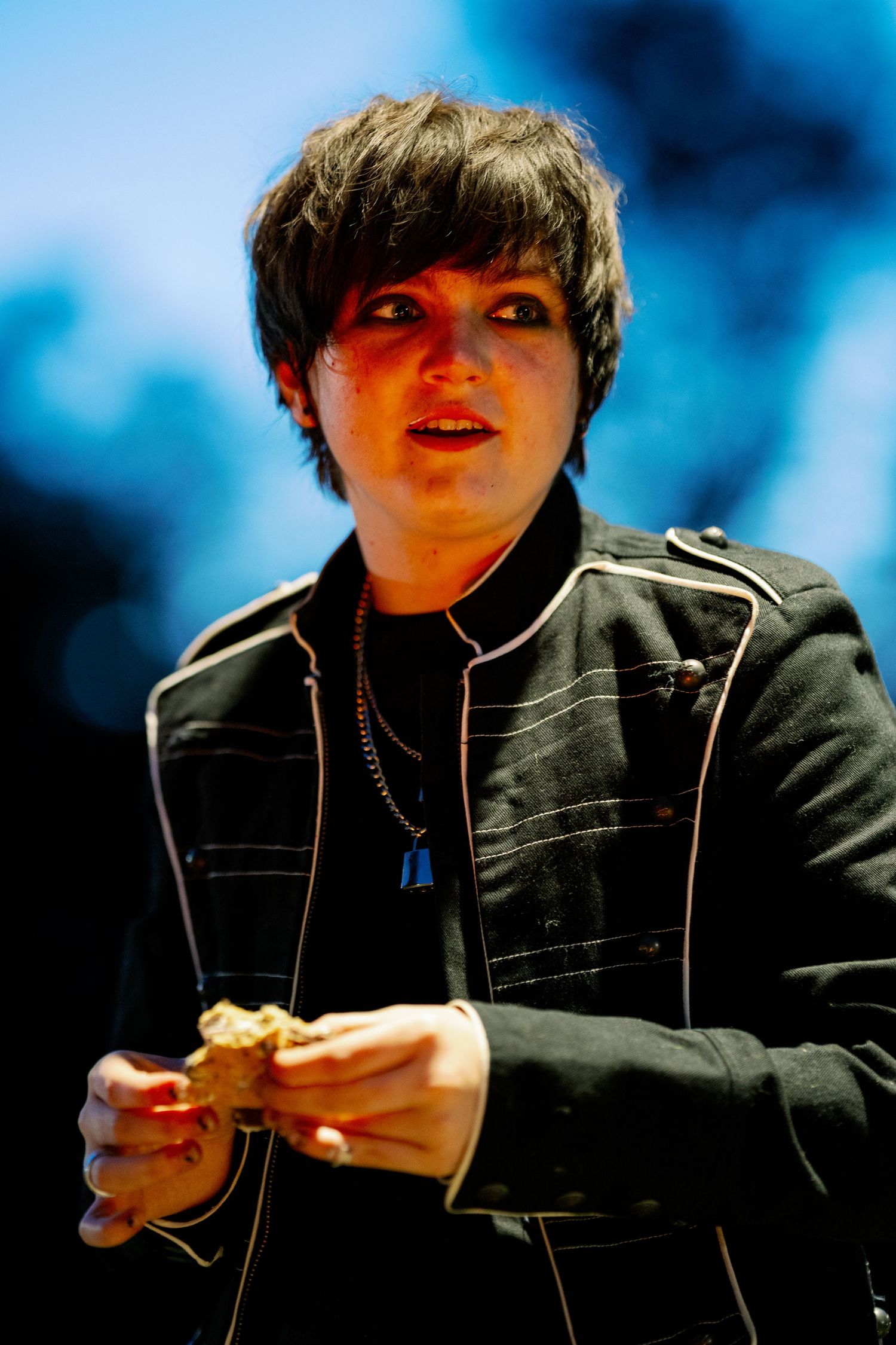 Person in black jacket eating and smiling with dramatic blue lighting in a series of sequential photos.