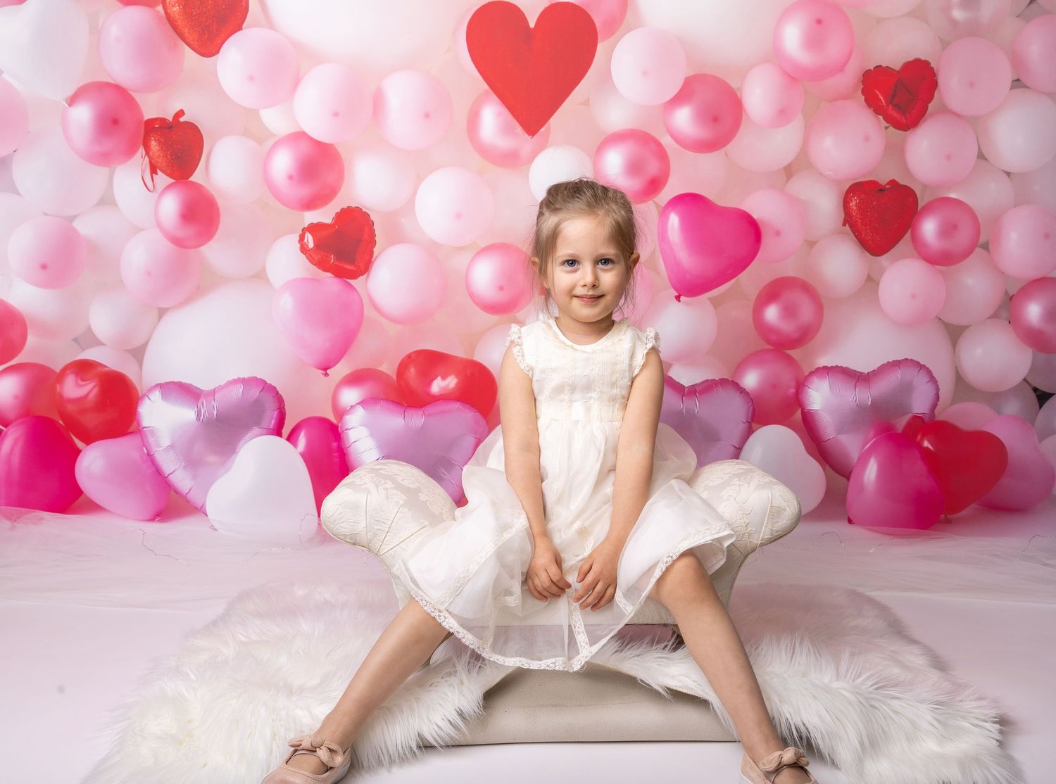 Baby during Valentine’s Day-themed cake smash in Glenview IL studio featuring heart-shaped balloons, pink and red decor, and festive setup.