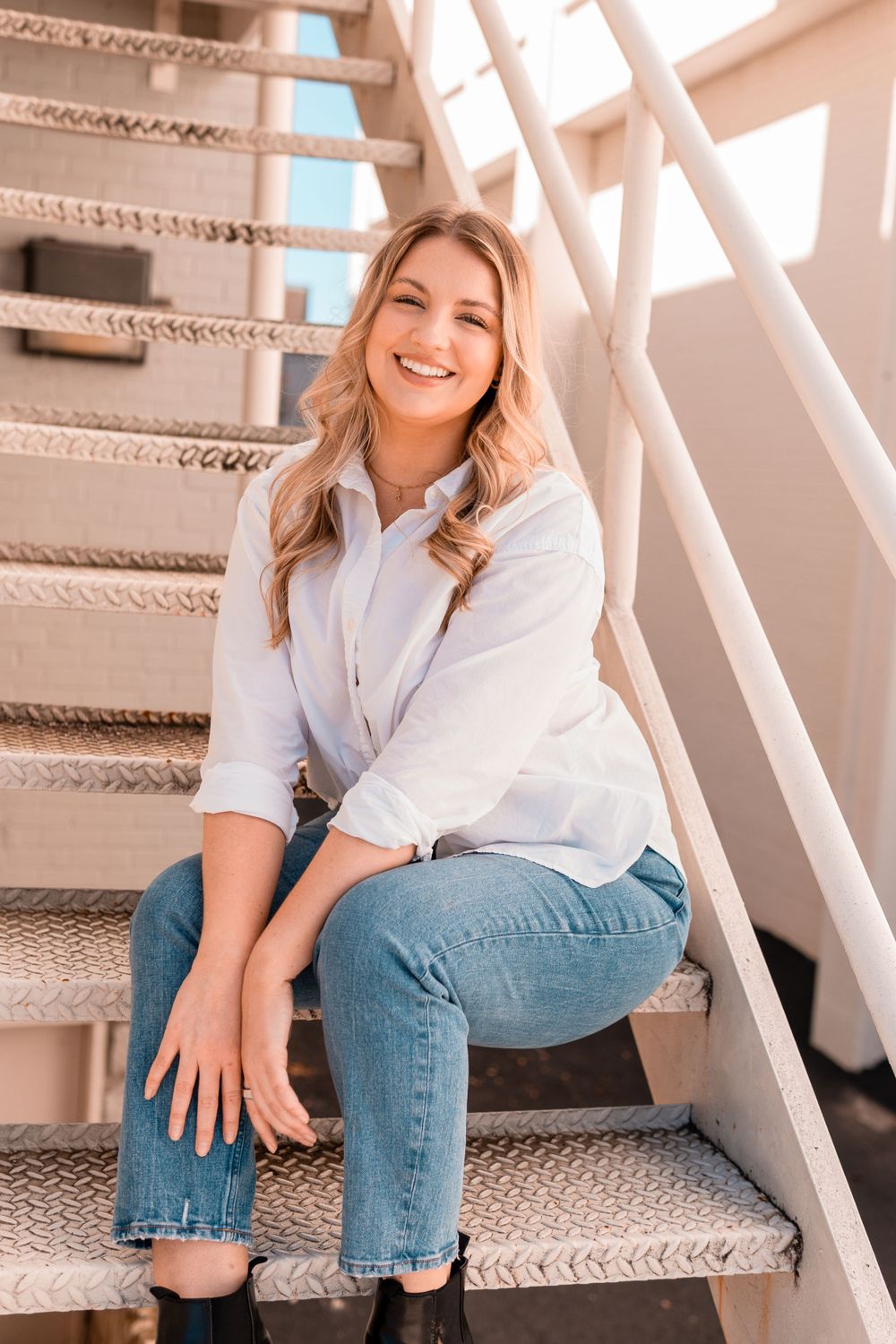 Casual lifestyle portrait on carpeted stairs wearing classic white shirt and jeans.