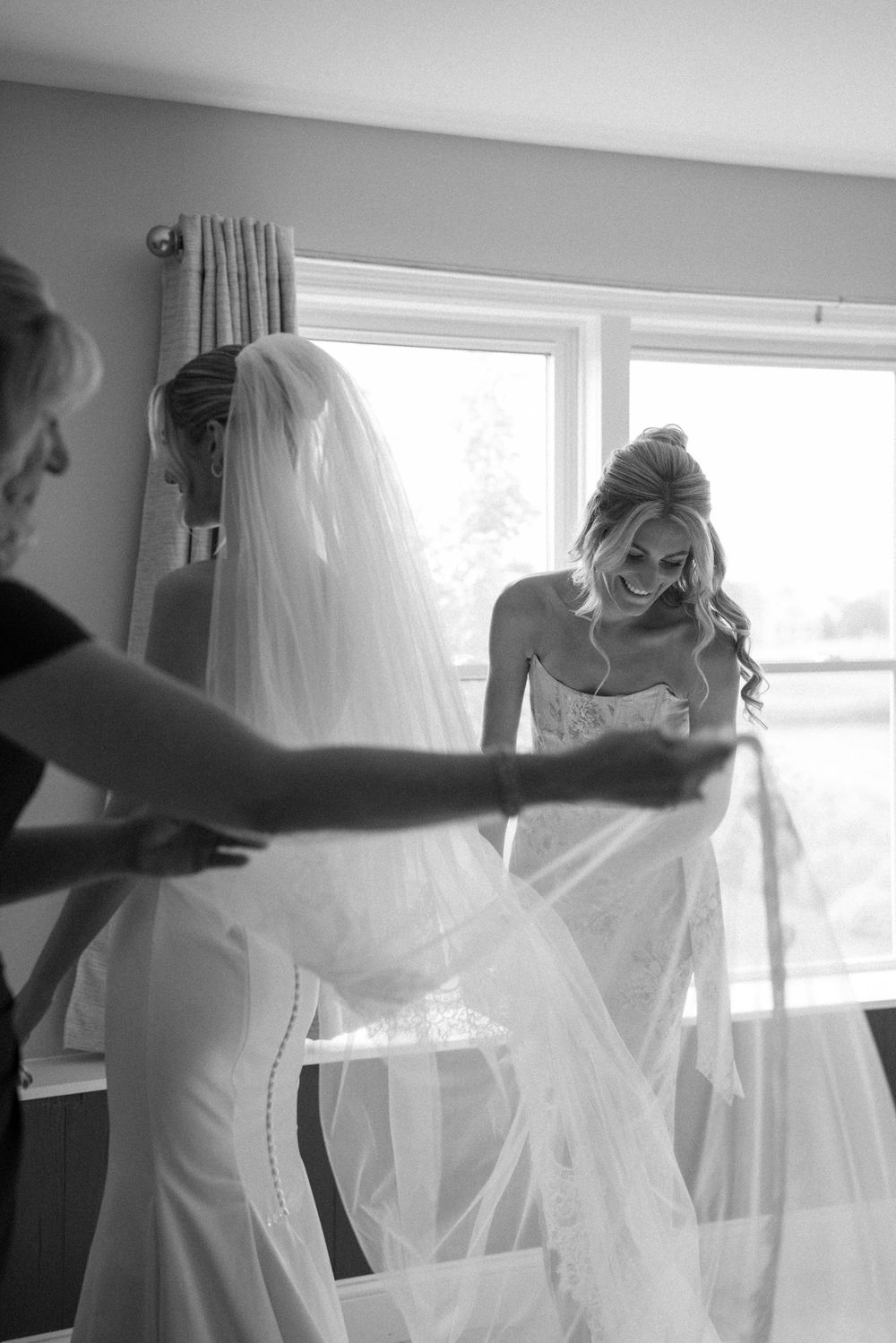 A series of black and white photos showing the preparation and adjustment of a wedding dress veil near a window.
