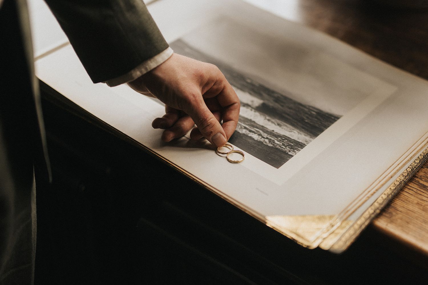 Hand touching wedding ring on vintage black and white photograph in album. Captured by Lincolnshire photographers.