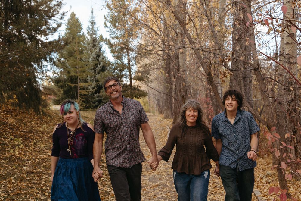 A casual family photo session with everyone sitting on a bench in fall weather.