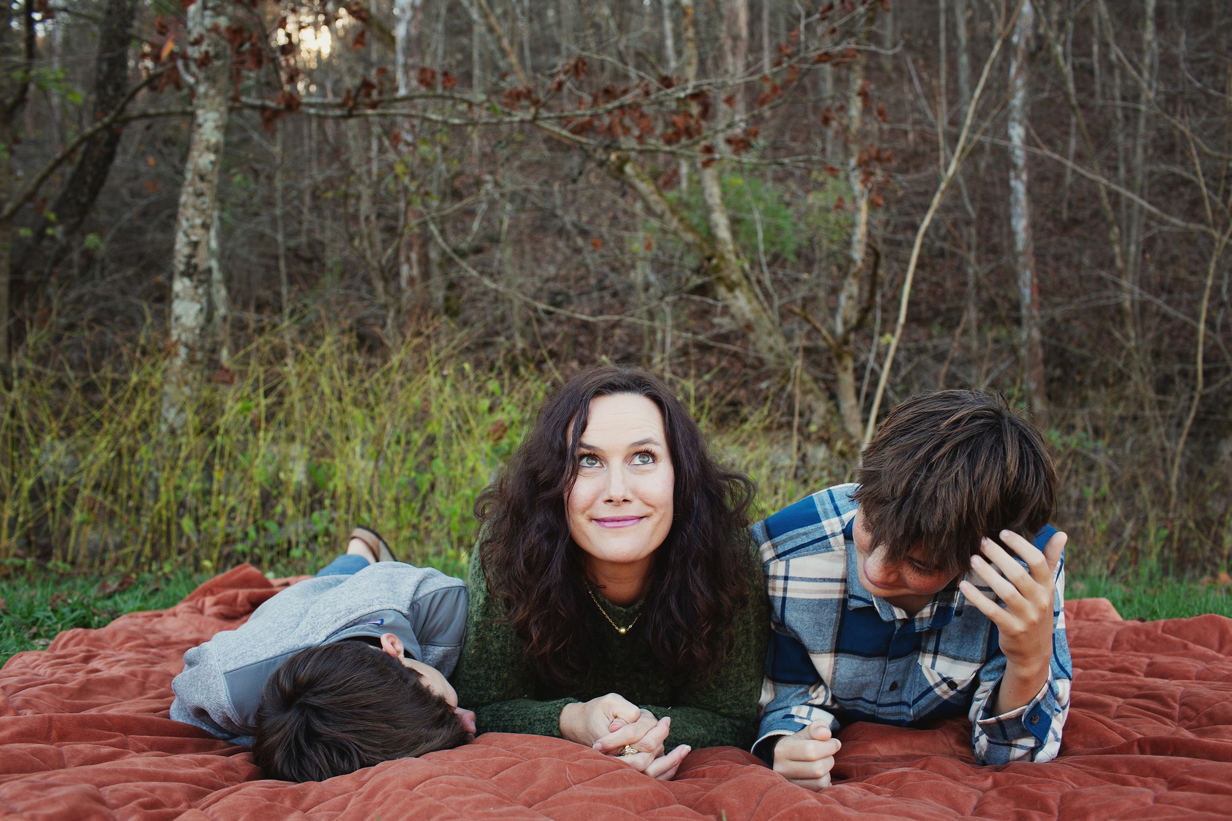 photo of a mom and her boys laying on a blanket on their property mom looking up to the sky candid photography