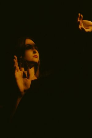 Artistic portrait silhouettes in warm orange lighting against dark background show dramatic upward gazing poses.