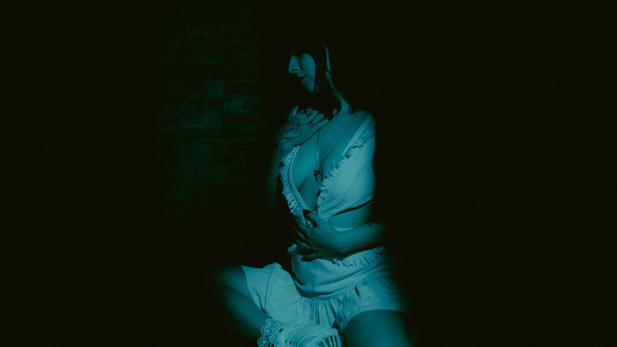 A dramatic teal-tinted photo series showing a person posing in low-light conditions against a dark background.