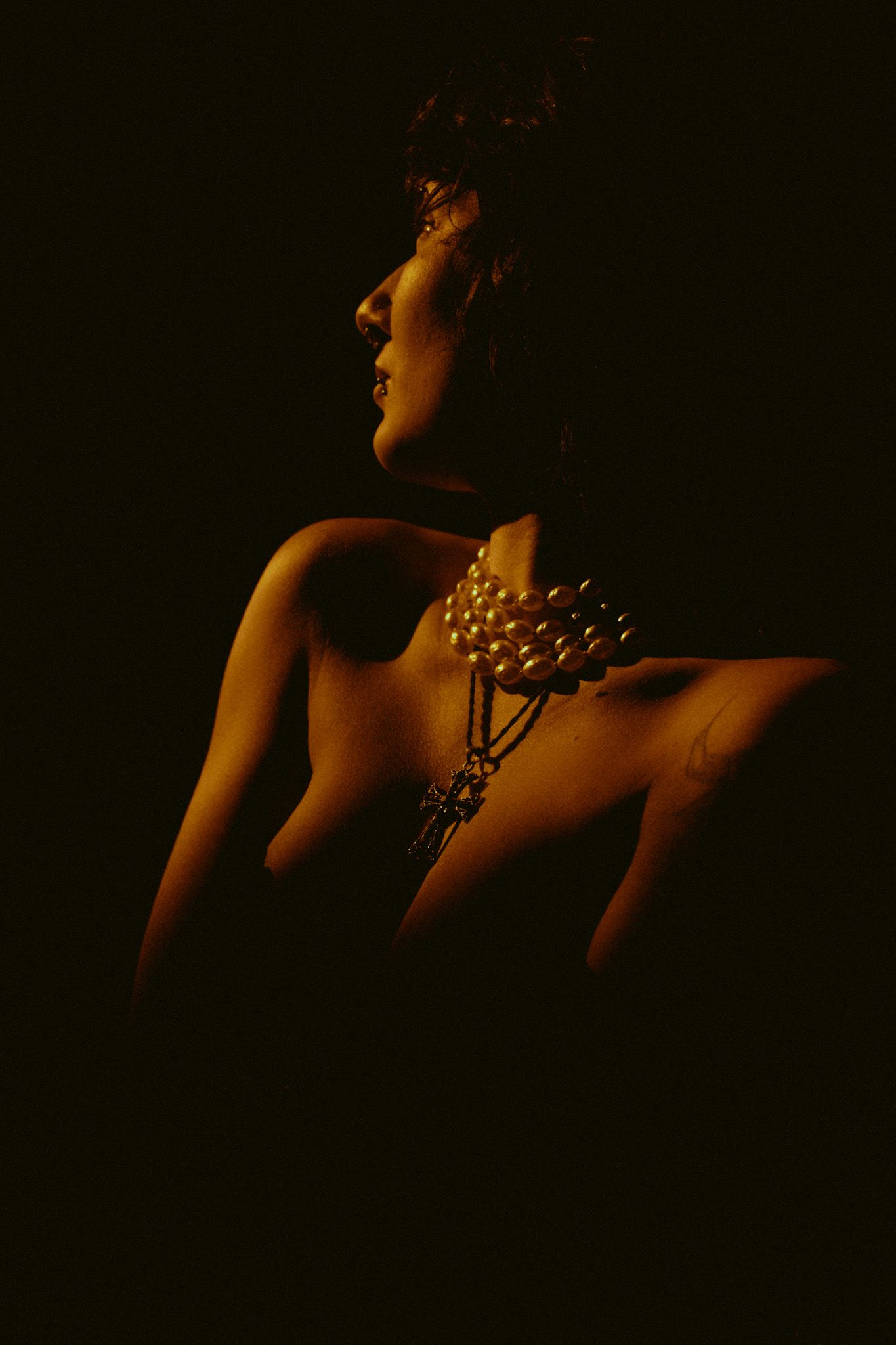 Artistic nude silhouette in dramatic low-key lighting with glowing highlights against dark background.