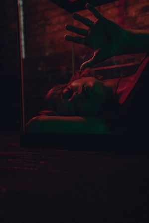 Silhouetted hands against a dark red background create a dramatic and mysterious atmosphere.