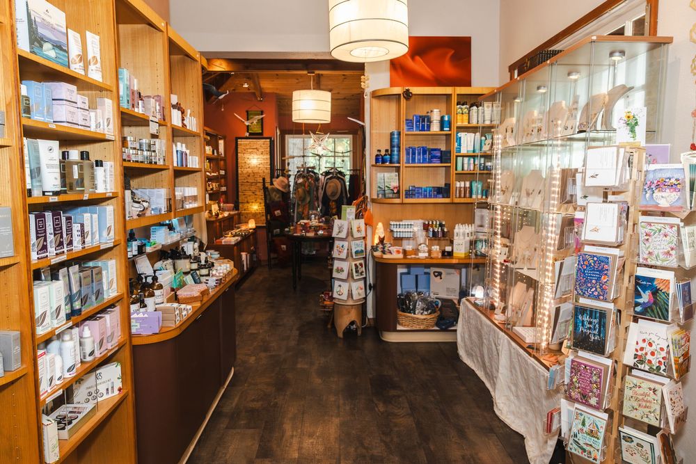 Interior of a cozy gift shop with wooden shelves displaying various retail products and greeting cards.