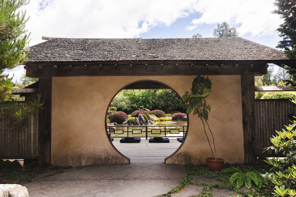 Panoramic view of a traditional Japanese zen garden with raked gravel patterns and covered walkways.