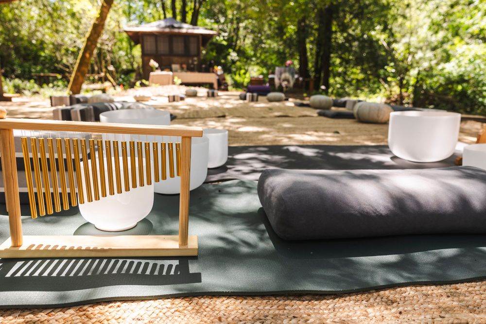 Zen garden seating area with comfortable cushions and wooden benches in dappled sunlight.