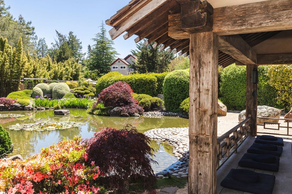 Rustic wooden pergola structure overlooking a serene garden landscape with blooming flowers.
