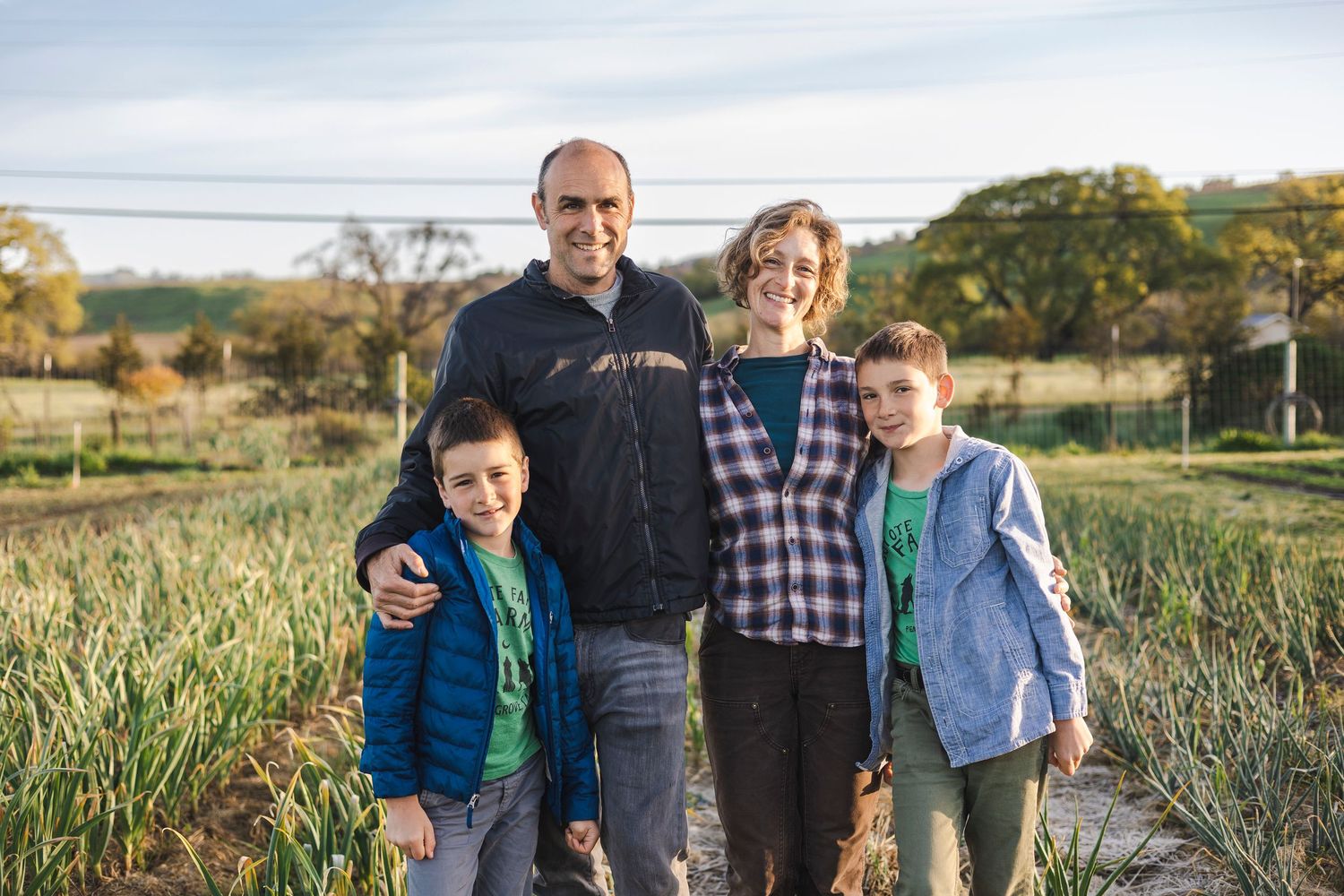 A family walks together through a scenic autumn field during golden hour.