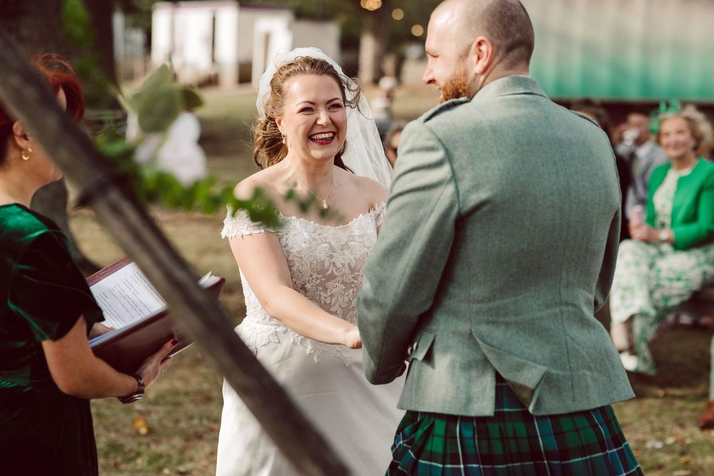 Couple exchanges rings during outdoor wedding ceremony with guests watching in natural setting.