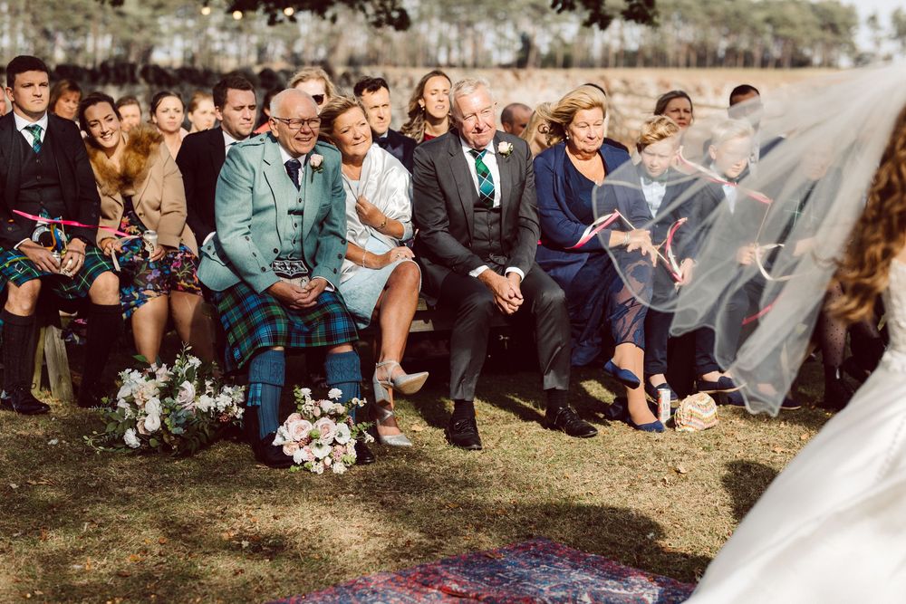 Wedding ceremony guests seated in rows on chairs at an outdoor venue.