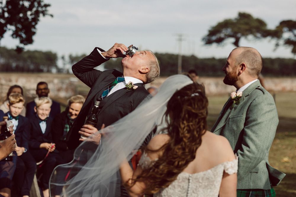 Wedding guests enjoy a unique whiskey barrel ceremony ritual in an outdoor setting.