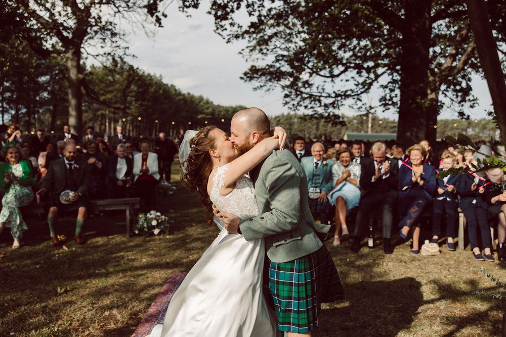 Couple participates in whiskey barrel ceremony during outdoor wedding celebration.