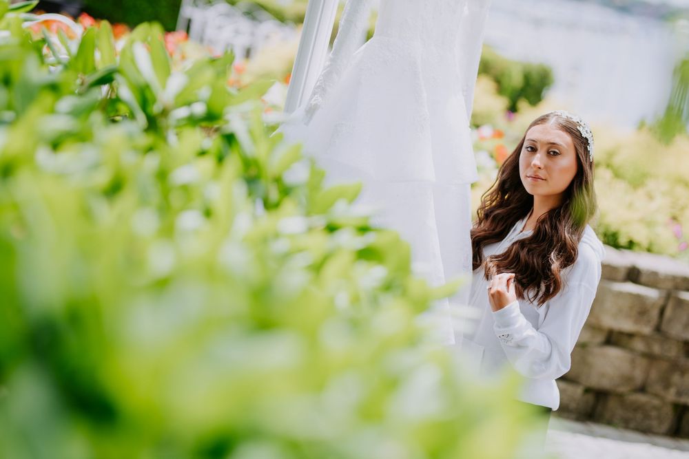 A dreamy outdoor bridal portrait session captured through green foliage in natural light.