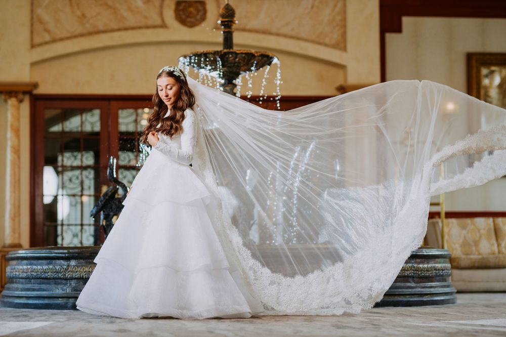 White wedding dresses displayed in a row at an elegant venue with ornate architectural details and marble columns.