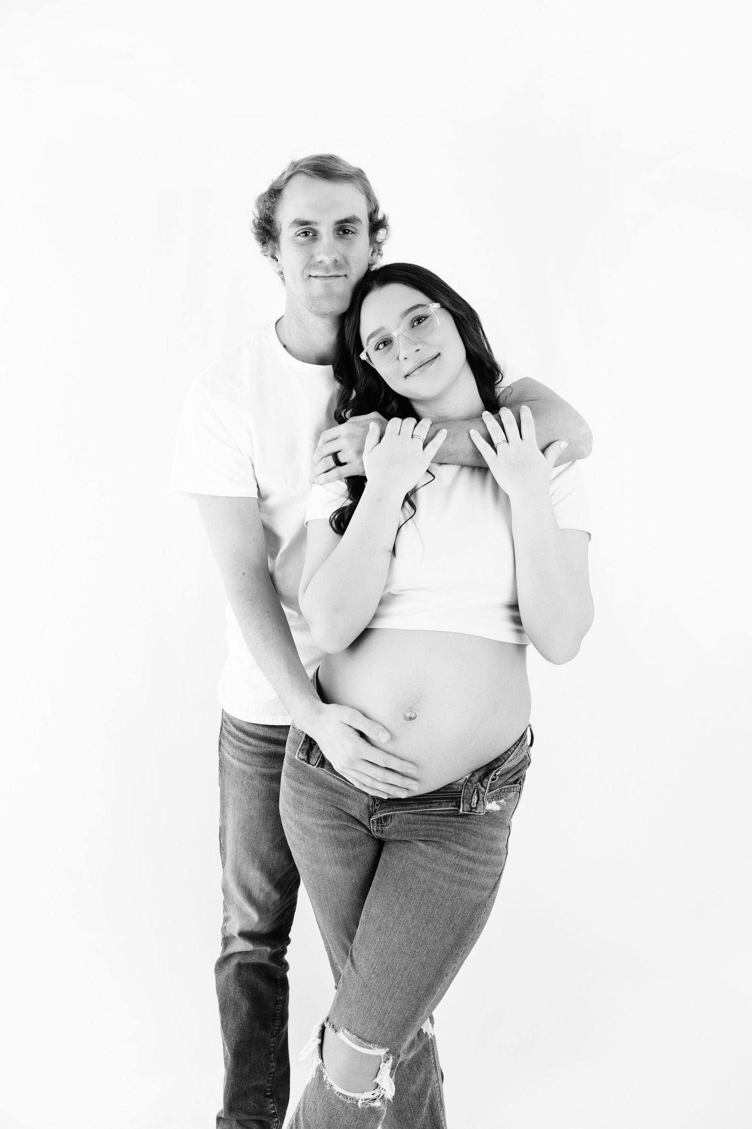 Black and white photo series showing a playful couple in casual clothing striking dynamic poses against a white backdrop.