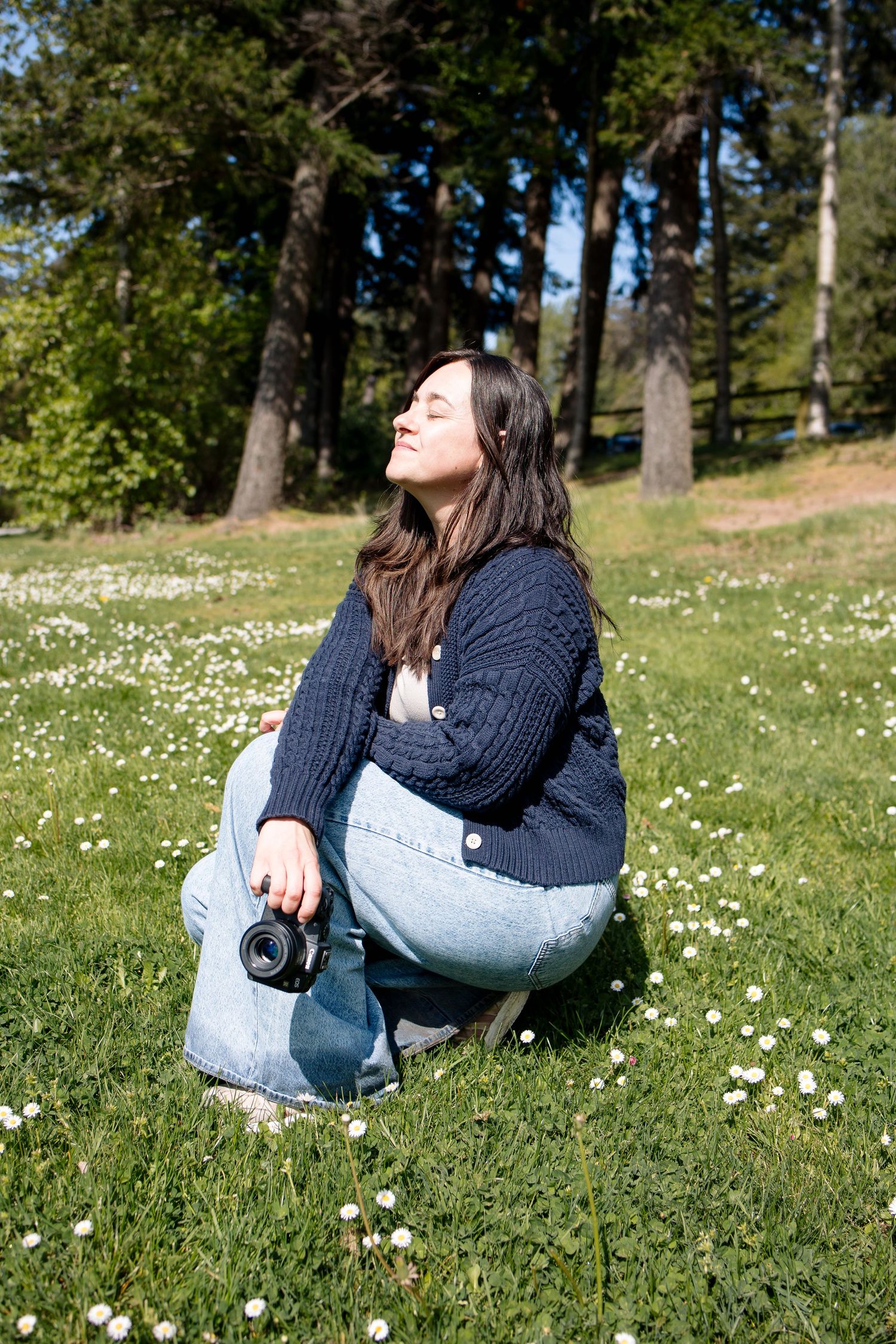 Person sitting in a blooming wildflower meadow on a sunny summer day wearing casual clothing.