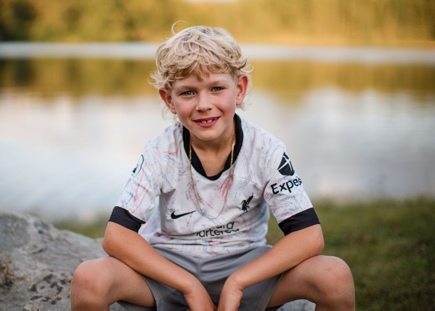 Natural family photography of a child sitting outdoors near water, photographed during a relaxed documentary family photoshoot