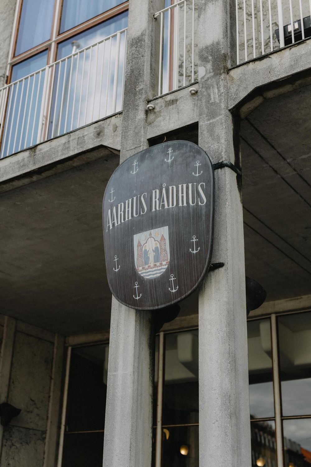 A vintage-style sign reading 'Aarhus Radhus' with anchor decorations mounted on a concrete building exterior.