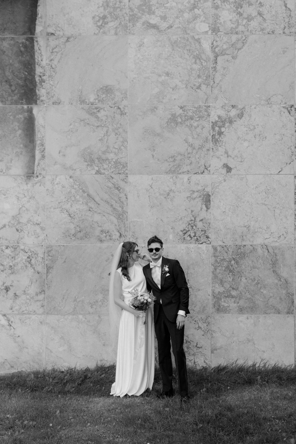 Black and white wedding portraits showing a couple posing against Aarhus Rådhus