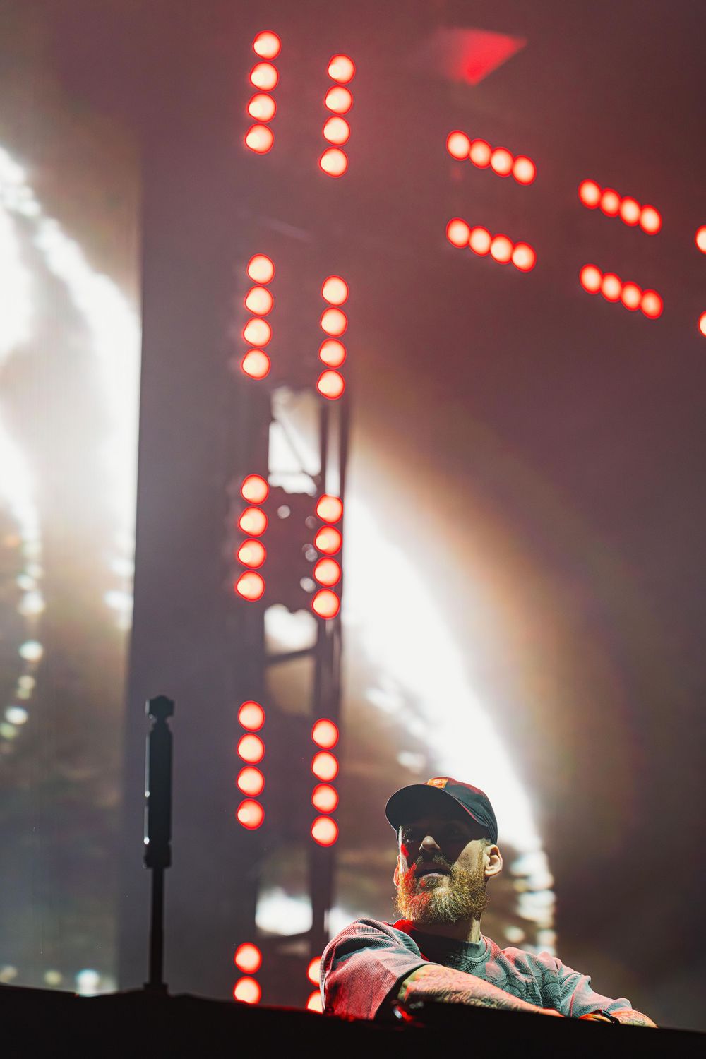 Concert performer silhouetted against dramatic red LED lights and stage fog during a live performance.