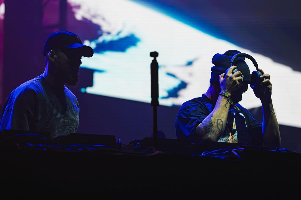 Silhouetted figures perform on stage with dramatic blue lighting and fog effects creating a theatrical atmosphere.