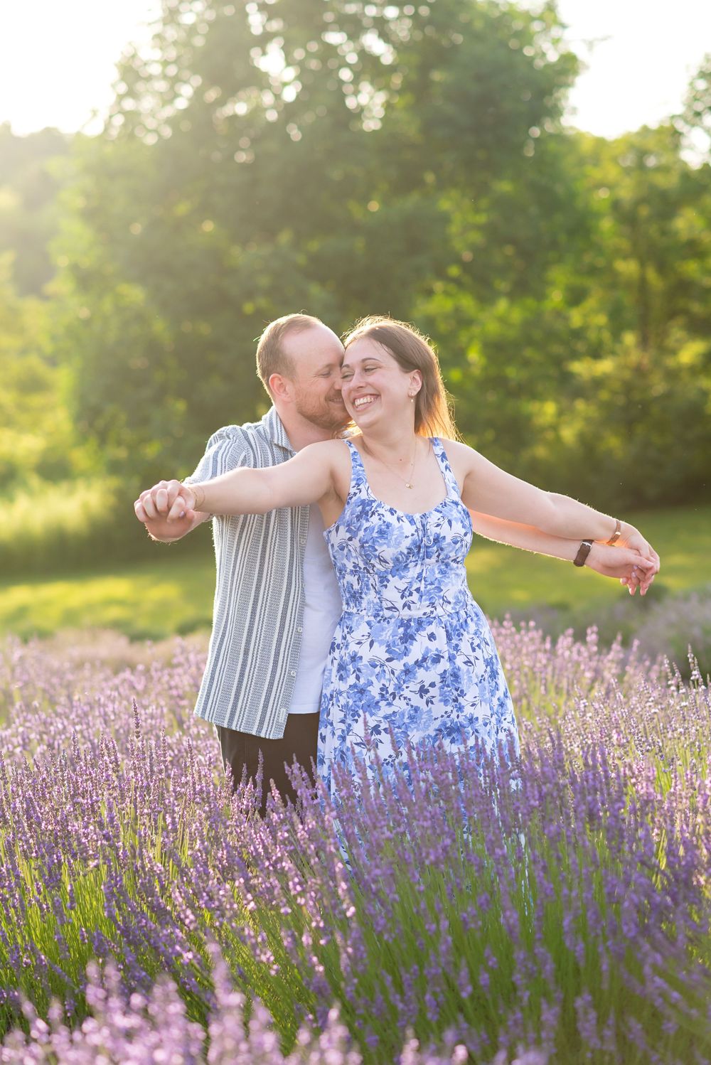 A couple dances together in a beautiful blooming lavender field at sunset, her blue floral dress swaying with the movement in R & B LAVENDER