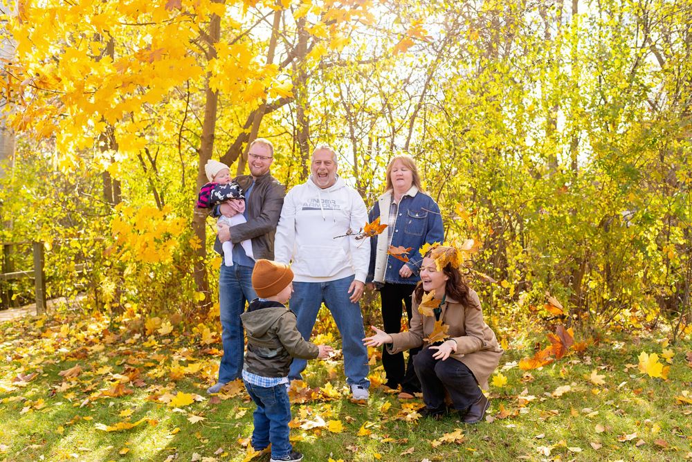 A group enjoying a fall photo session surrounded by vibrant yellow foliage in a wooded setting in cambridge.