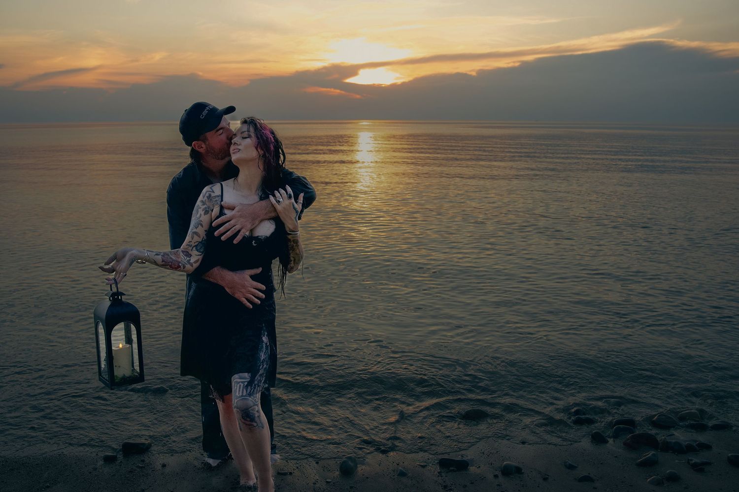 Romantic couple silhouetted against golden ocean sunset creating intimate moment on beach.