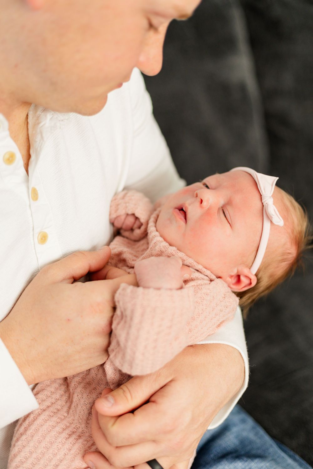 Tender moment between parent and baby in pink outfit.