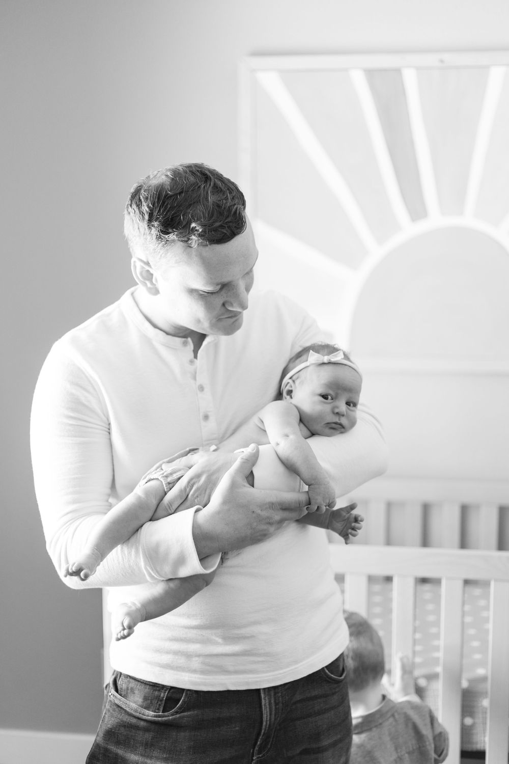 Black and white series showing intimate moments between parent and baby in front of a crib.