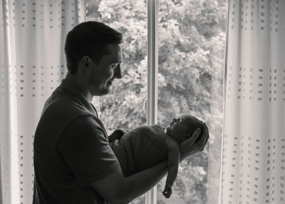 Black and white silhouette of people standing by window.