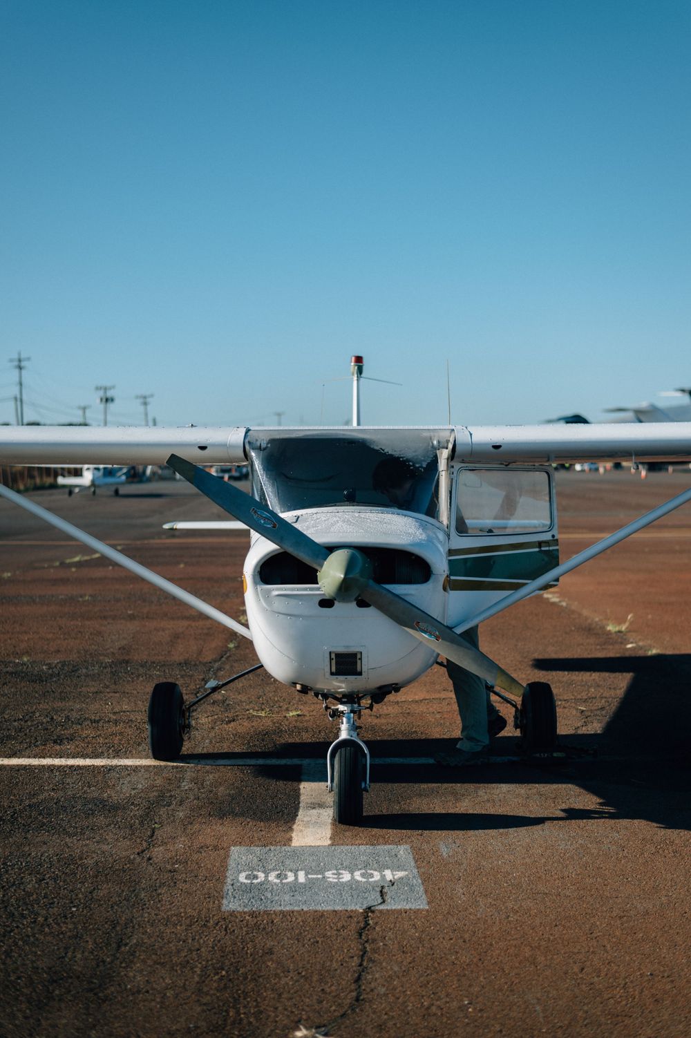 Front view of white Cessna aircraft parked on marked spot at desert airfield.