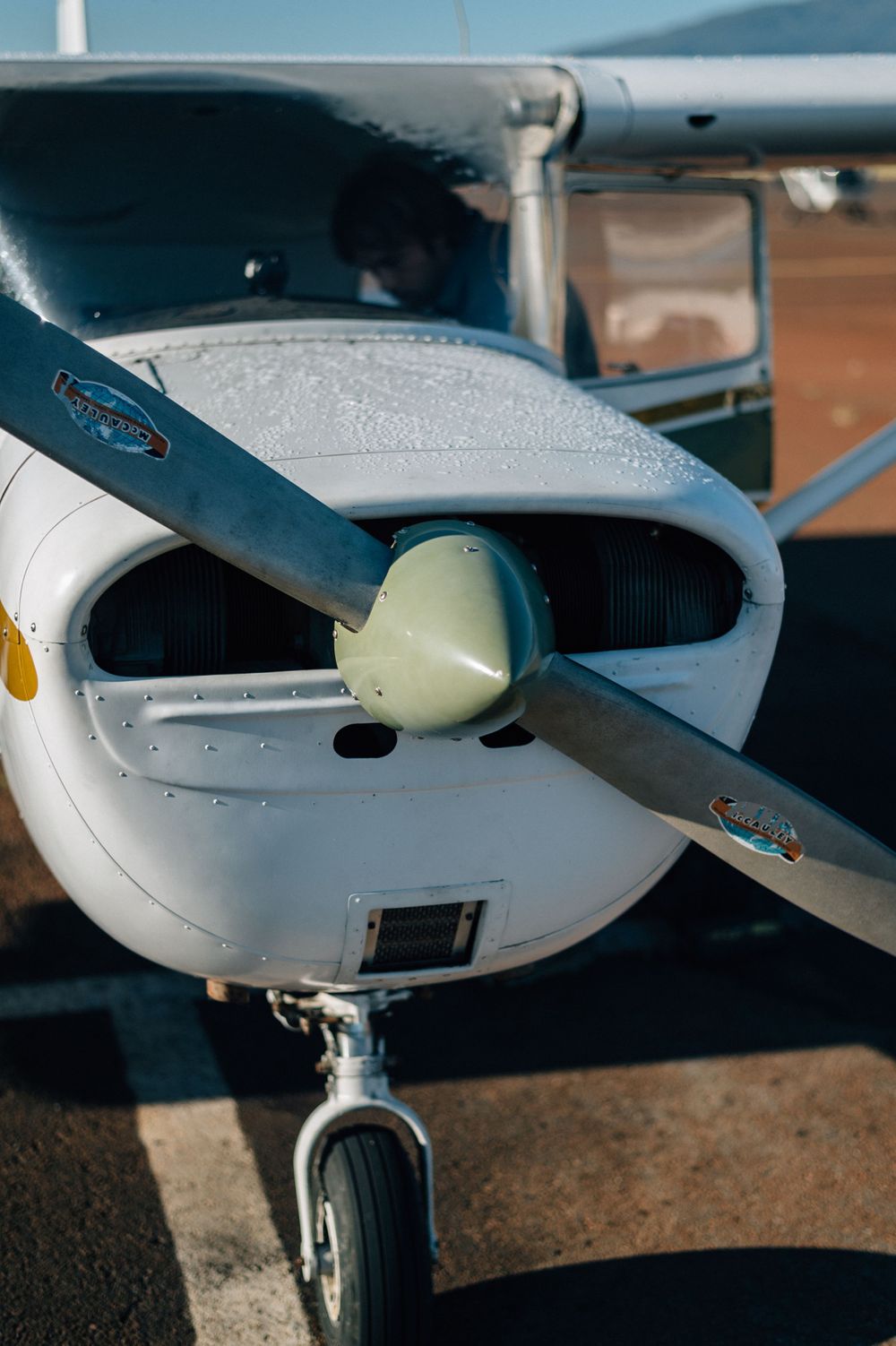 Close-up view of a small aircraft's white exterior and propeller against a blue sky.