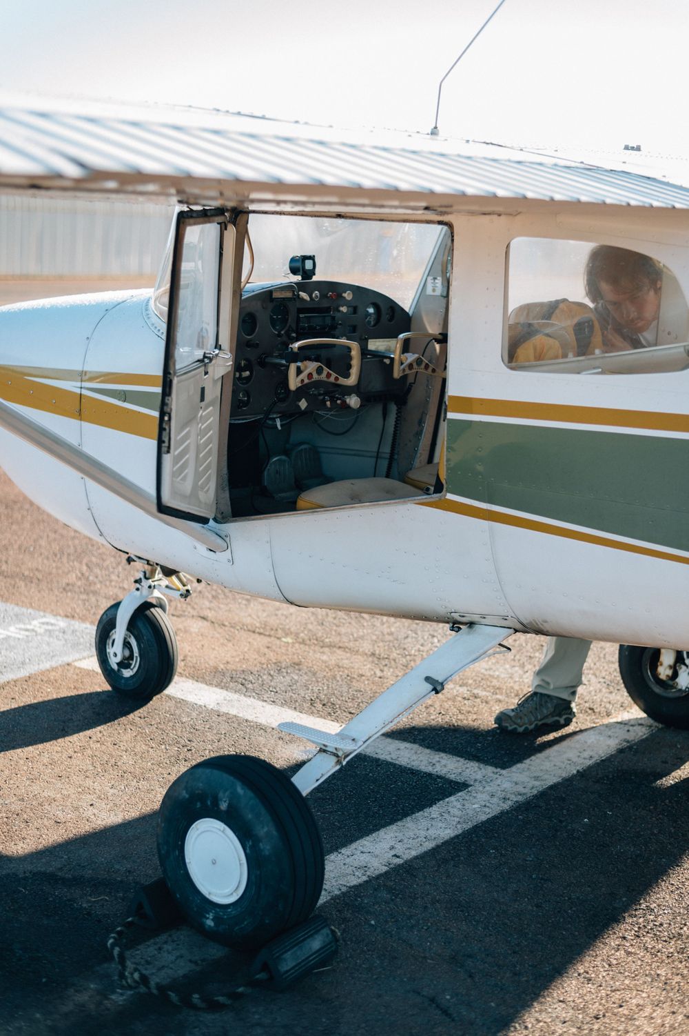 Landing gear and undercarriage details of a white and gold private aircraft on ground.