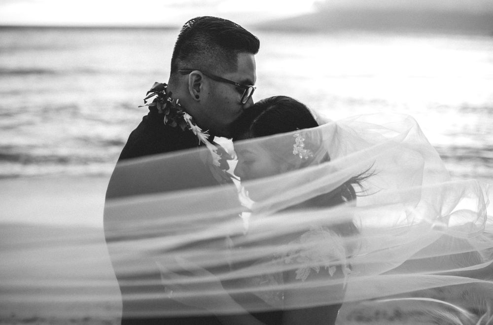 Romantic black and white beach wedding portrait with flowing veil.