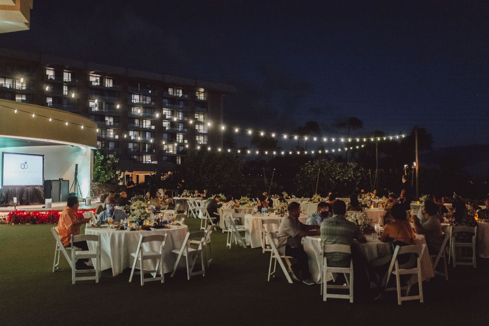 Evening outdoor wedding reception with string lights illuminating tables and chairs.