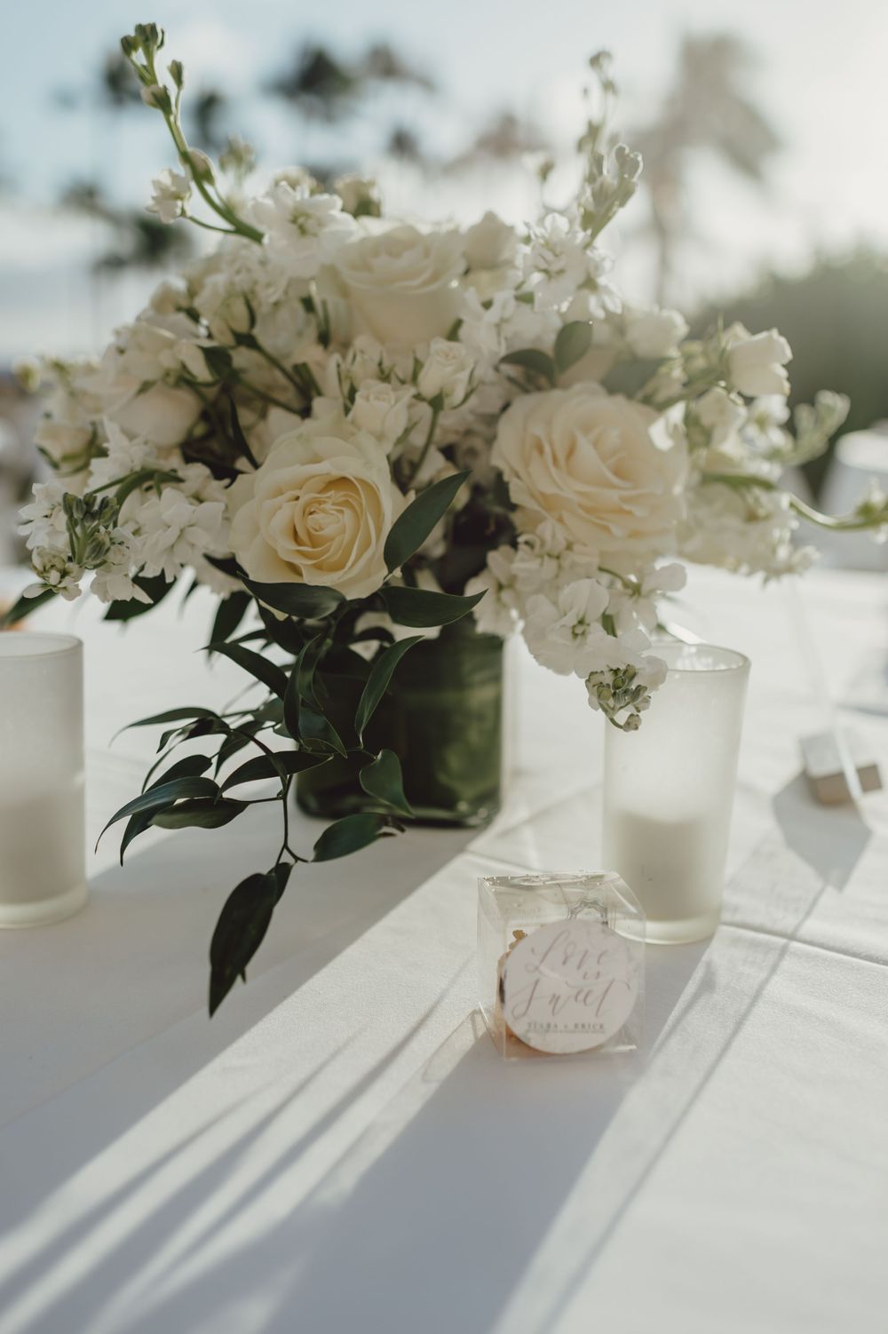 Elegant white rose and baby's breath centerpiece arrangement in glass vase with soft natural lighting.