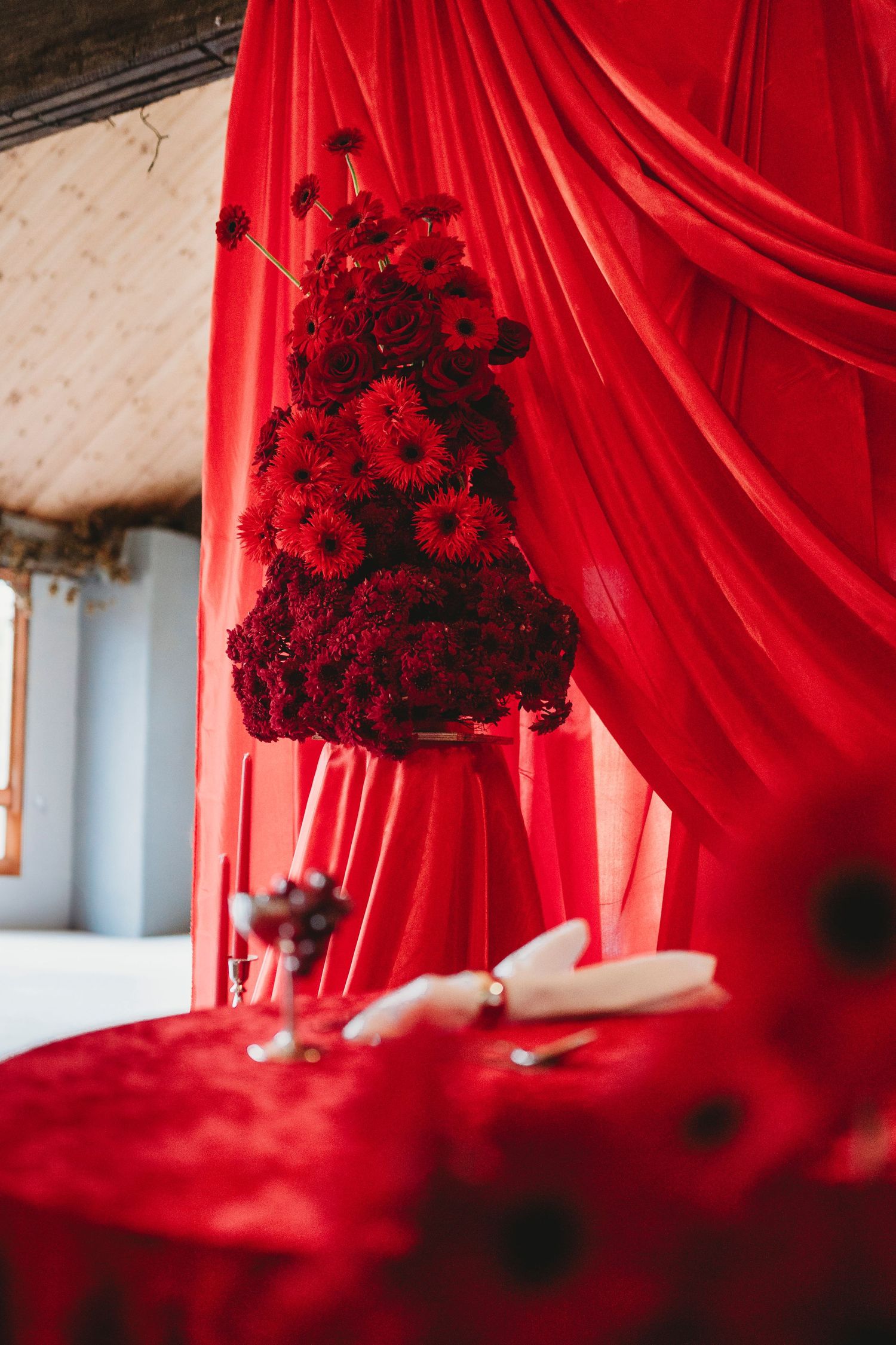 A series of elegant red curtain drapes with dark floral arrangements creating a dramatic romantic atmosphere.